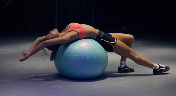 a woman laying on a gymnastic ball in a gym