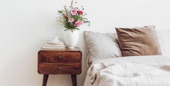 a bedroom with a bed and a table with a vase of flowers