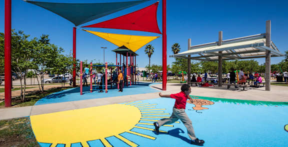 A child runs on a playground with a sun design on the ground.