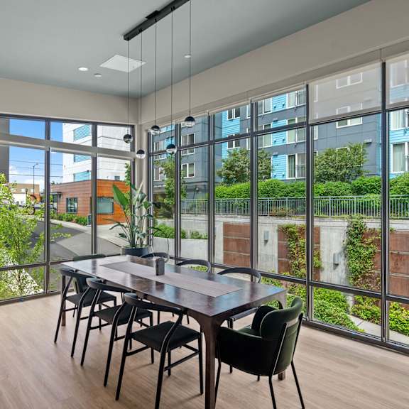 A dining table with chairs in front of a glass wall with a view of a building.
