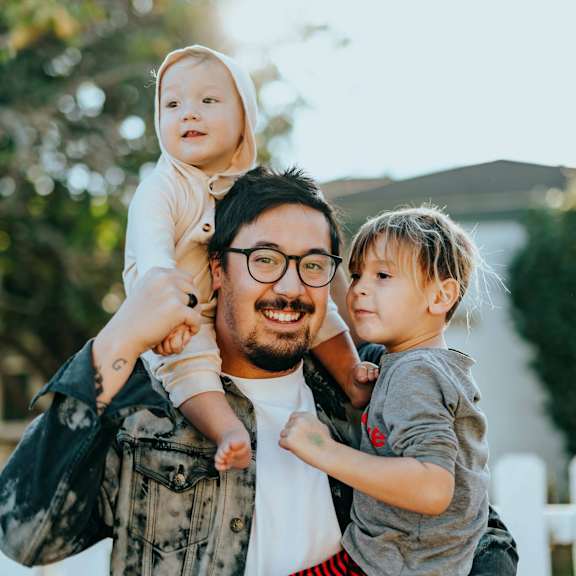 A man is carrying two children on his shoulders.