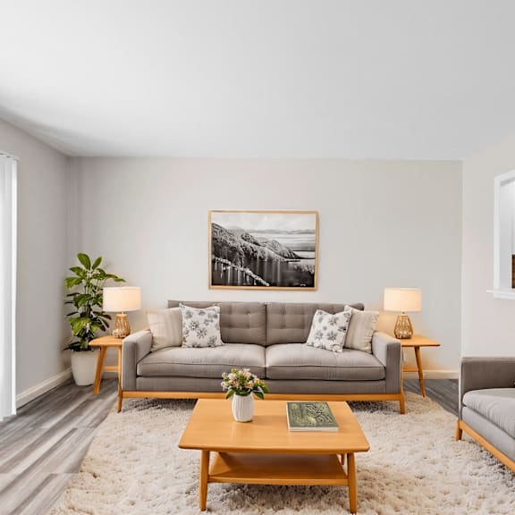 A living room with a grey couch, a wooden coffee table, and a painting on the wall.