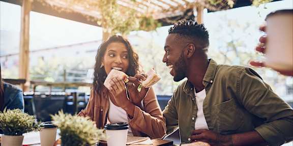 a man and woman eating sandwiches at a restaurant