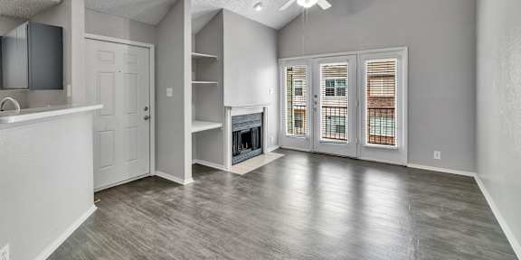A spacious room with a ceiling fan and a door leading to a balcony.