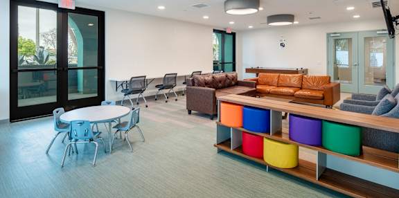 A conference room with a white table and chairs, a couch, and a TV.