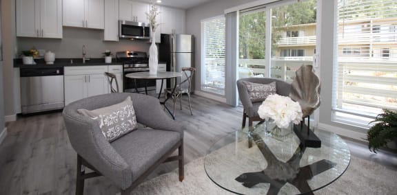 a living room and kitchen with a glass table and chairs