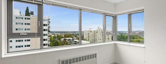 an empty room with windows and a radiator and a city view