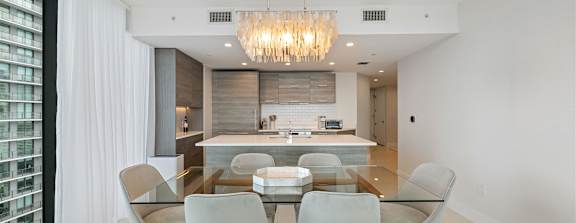 A modern living room with a large window and a flat screen TV mounted on the wall.