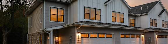A modern house with a large front yard and two garages.