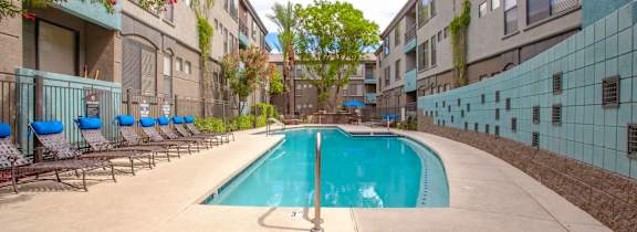 A swimming pool in front of a building with a palm tree.