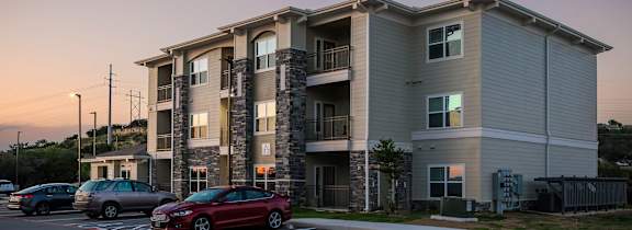 Apartment building with a car parked in front.