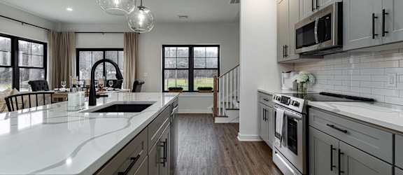 A modern kitchen with wooden shelves and black countertops.