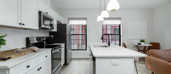 A modern kitchen with wooden shelves and black countertops.