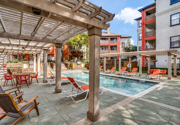 A pool area with chairs and a table.