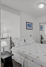 A bedroom with a bed, nightstand, and a painting on the wall.