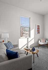 A living room with a grey couch, a coffee table, and a chair.