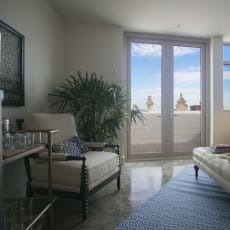 a living room with a view of the beach and a couch and chair