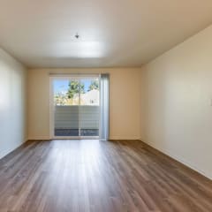 A room with wooden floors and a sliding glass door leading to a balcony.at Emerald Pointe, Rohnert Park, 94928
