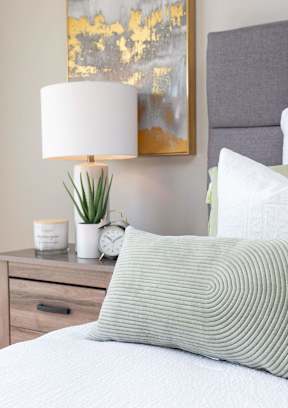 A bedroom with a bed, nightstand, and a painting on the wall. at Two Rivers Home Rentals, West Des Moines, IA 50266