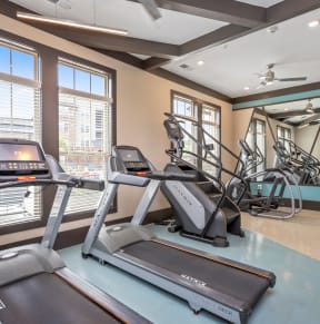 a gym with treadmills and other exercise equipment and windows at Residence at Riverwatch in Augusta, GA 30909