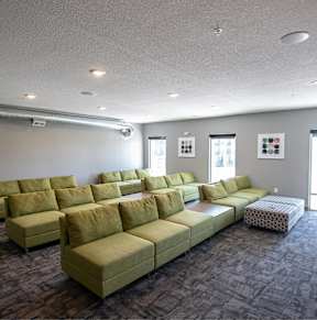 A room with a carpeted floor and a long couch.at Linc, Des Moines Iowa