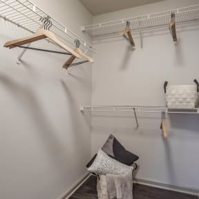 a walk in closet with shelves and hooks and a chair