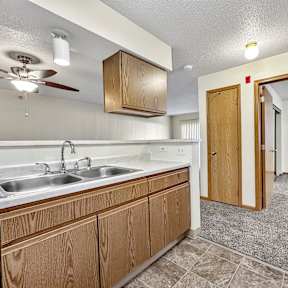 A kitchen with wooden cabinets and a black dishwasher. at Somerset Apartments, Des Moines, IA, 50315