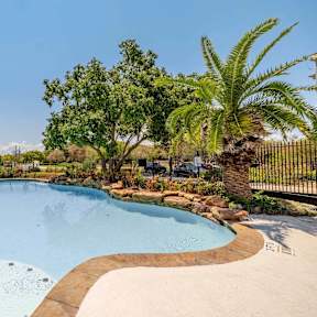A large swimming pool in front of a multi-story apartment building.