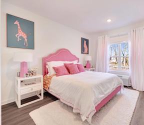 a pink and white bedroom with a bed and a window at The Franklin at Hillsborough Apartments, Hillsborough, NJ