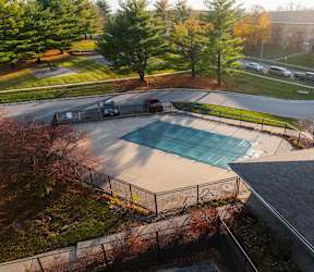 A swimming pool surrounded by a fence and trees at Rosemont Place Apartments, Des Moines, IA, 50320