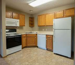 A kitchen with white cabinets and a bar area with stools at Peach Tree Apartments, Ankeny, IA