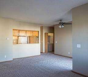 an empty living room with a kitchen and a ceiling fan at Sunrise Meadows, Waukee, IA, 50263
