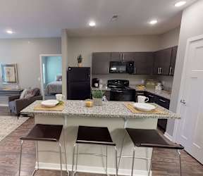 A kitchen with a countertop and bar stools at The Barclay Apartments, Altoona, IA, 50009