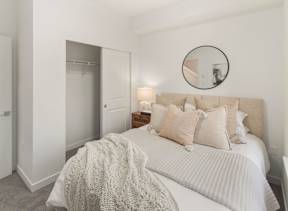 A bedroom with a bed, pillows, and a round mirror on the wall. at The Narrows at Clare Apartments , Apartments, Bremerton, WA
