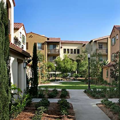 A pathway leads through a landscaped courtyard between two rows of apartment buildings.