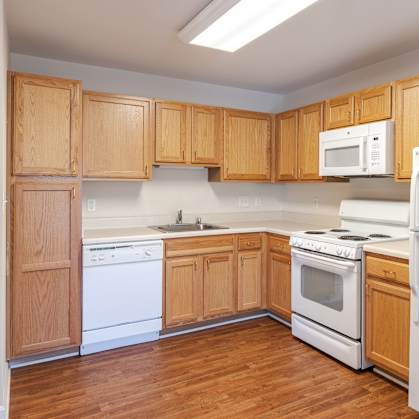 A kitchen with wooden cabinets and white appliances.at The Gardens of Stafford, Virginia, 22556
