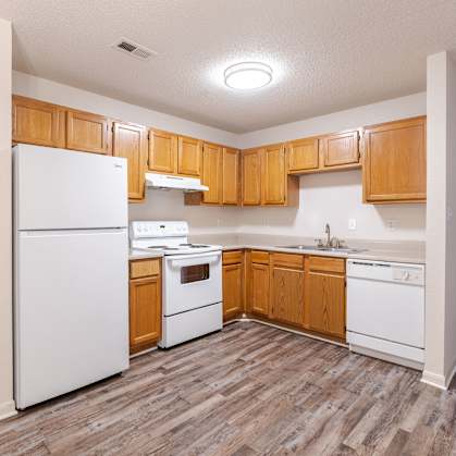 A kitchen with wooden cabinets and white appliances.at The Village at England Run, Virginia