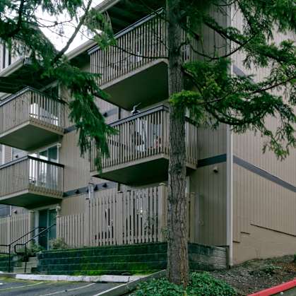 Apartment building with balconies and trees in front.