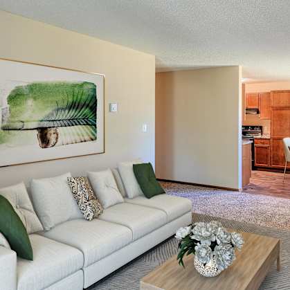 a living room with a couch and a coffee table in front of a dining room. Grand Forks, ND Madison Apartments