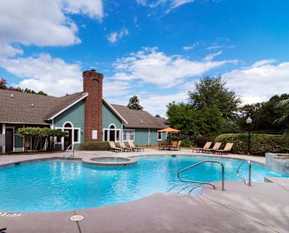 A large outdoor swimming pool with a slide and sun loungers.