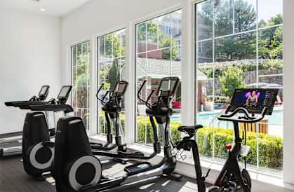 a gym with exercise equipment and windows overlooking a pool at Residences at Stevens Pond, Saugus, Massachusetts 01906