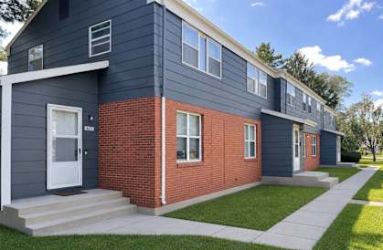 A modern two-story house with a blue exterior and a red brick section.