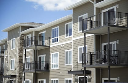 A row of apartment buildings with balconies and black railings.