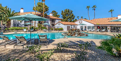 a swimming pool with chairs and umbrellas in front of a resort style pool