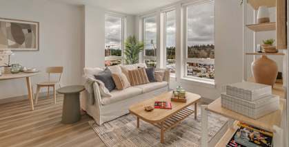 A living room with a couch, a coffee table, and a large window at Nook at Northaven Apartments, Washington 98125