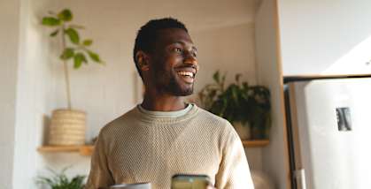 A man is holding a cup and a phone in his hands.
