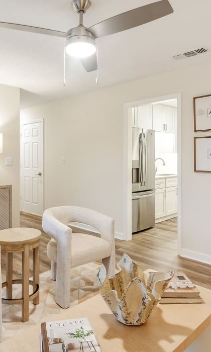 A living room with a white chair, a wooden table, and a painting on the wall. at The Oliver Apartment Homes in Olive Branch, MS 38654