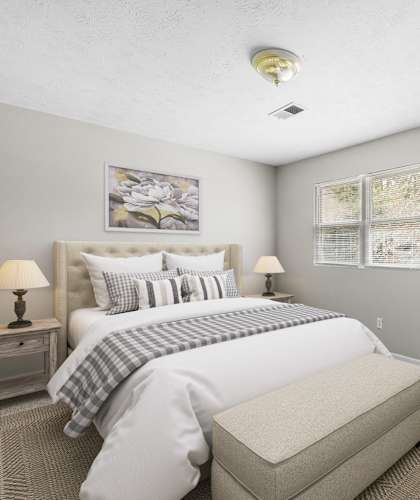 A well-lit bedroom with a large bed, a chair, and two lamps at Bradford Gwinnett Townhomes in Georgia 30071