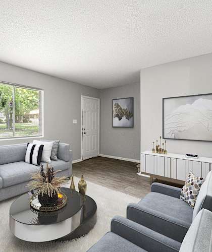 A living room with a grey couch, a coffee table, and a painting on the wall at Northgate Townhomes in Tucker, Georgia