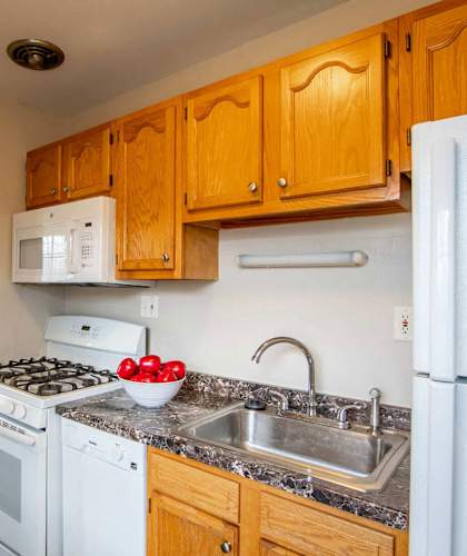 A kitchen with a stove, oven, refrigerator, and sink. at Michigan Street Apartment Homes, Michigan